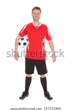 Portrait of young soccer player holding football over white background