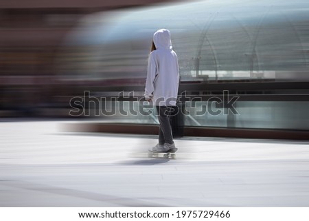 a girl in a hood is riding a skateboard around the city