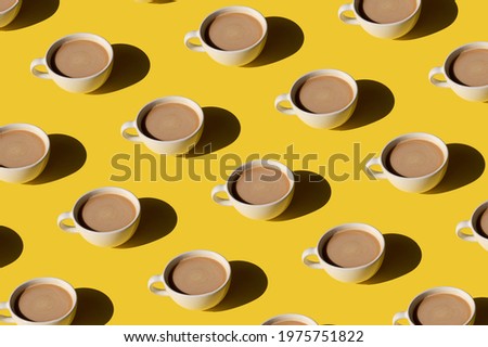 White cup of coffee with milk pattern on yellow background. Sunlight minimal trendy concept