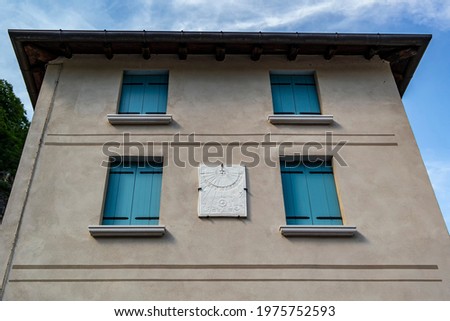 House with blue window frames and antique sundial