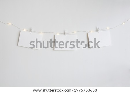Three horizontal blank cards mockup hanging by small clothespins on an LED light string. Modern and minimalist.