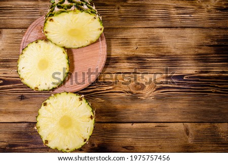 Cutting board with sliced pineapple on rustic wooden table. Top view