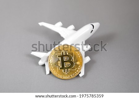 Blockchain airline ticket concept. Bit coin digital currency cryptocurrency. Gold coin, plane on grey background. Color year 2021 illuminating and ultimate gray pantone.