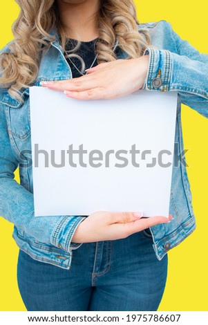 A young girl poses on a yellow background holding a white diary.Studio concept