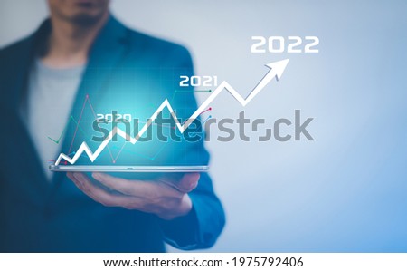 Businessman holding tablet bar graph of analytics and financial, Changes in new planning, Business growth, ideas and perspectives, Stock investment, and dividends yield from business in 2020-2022