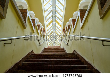 From below stairway decorated with white lamps under stained glass ceiling at daytime