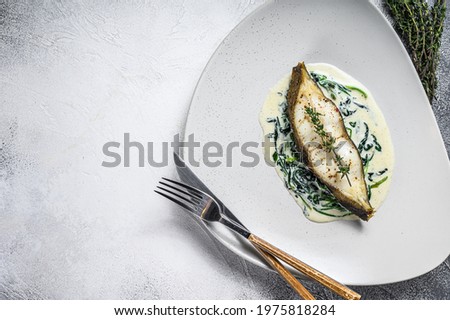 Baked Halibut fish steak with spinach. White background. Top view. Copy space
