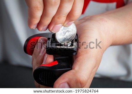 Close up isolated image of a person screwing a metal screw using a quarter dollar coin. He places the coin in the grove on top of the screw and twists it around by applying basic force. A quick tip.