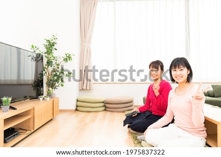  asian parent and daughter watching TV in living room