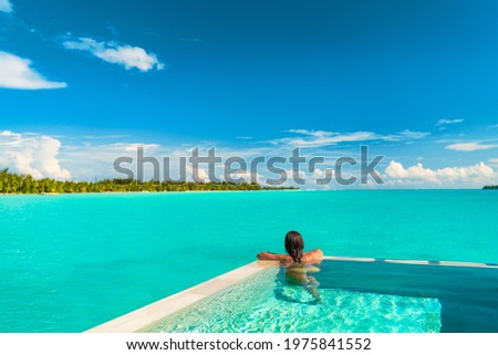 Luxury swimming pool spa resort travel honeymoon destination woman relaxing in infinity pool at hotel nature background summer holiday. Royalty-Free Stock Photo #1975841552