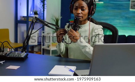 African woman recording video vlog and sharing content on streaming platform using social network, checking sound at mixer. Influcencer in digital marketing doing brodcast speaking during