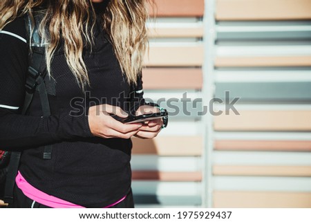Unrecognizable sporty Woman using phone after exercising outdoors.