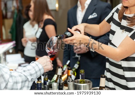 the girl with the bracelet pours wine into another person's glass