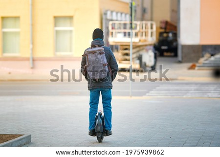 Man ride on electric unicycle on city street. Personal mobility, individual transportation vehicle. Mono wheel - vehicle for travel. Boy with backpack on electric mono-wheel (EUC) Royalty-Free Stock Photo #1975939862