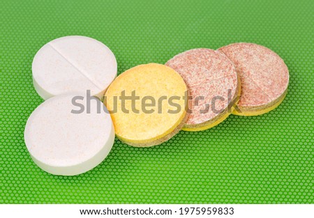 Different effervescent tablets of pharmaceutical product on a green surface, close-up in selective focus
