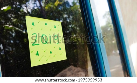 2019 text photo with green paper on house window glass background