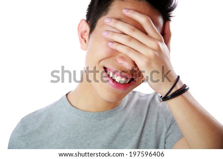 Portrait of a young man covering his eyes with his hand over white background