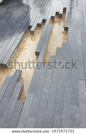 Wet pavement with missing rectangula blocks