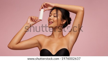 Attractive asian woman advertising for new cosmetic product. Female model promoting new skin care product. Royalty-Free Stock Photo #1976002637