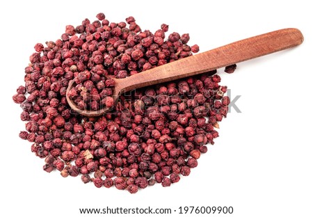 wood spoon on pile of dried magnolia berries (Schisandra Chinensis seeds) on white background
