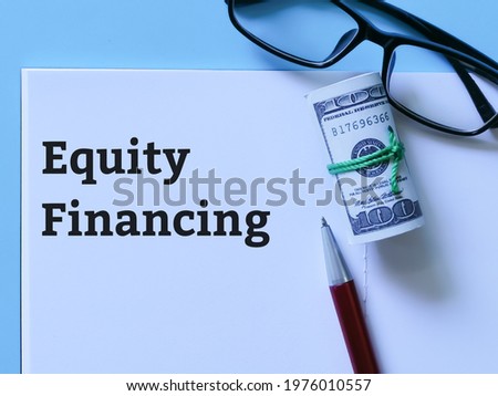 Business and finance concept. Top view phrase equity financing written on notebook with a pen,calculator,fake money and eye glasses.