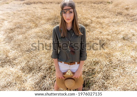 Portrait of a young female model with a stylish outfit and decorative jewelleryon her head posing for the photo in the outdoor natural environment. Beauty and fashion photography.