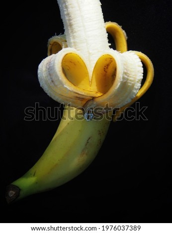 The peeled banana forms a heart-shaped​ with​ black​ background​, abstract picture.