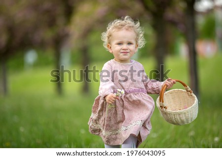 Beautiful toddler blond child, cute little girl in vintage rose dress, playing in the park springtime, cherry blossom garden