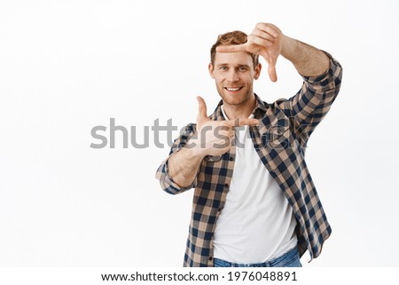 Smiling handsome redhead guy making hand frames, camera gesture and take picture in his memory, snap moment, looking happy, standing over white background