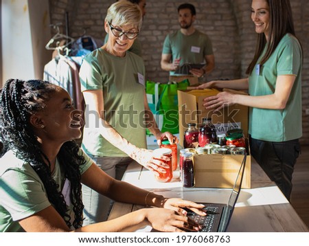 Group of volunteers with working in community charity donation center. Royalty-Free Stock Photo #1976068763