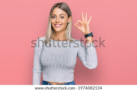 Beautiful blonde woman wearing casual clothes smiling positive doing ok sign with hand and fingers. successful expression. 