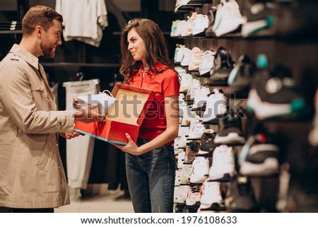 Young man choosing sneakers at sportswear shop