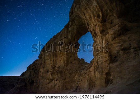 Beautiful starry night sky over the desert arch at Timna Valley Park, popular archaeological and tourist destination in southern Israel, southwestern Arava (Arabah), Eilat Mountains