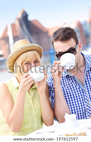 A picture of a young couple drinking coffee in an outside cafe in Gdansk marina