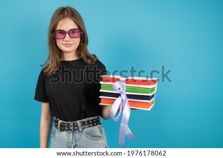 Close-up portrait of attractive cheerful brown-haired teenage girl embracing pile book science lover isolated on blue background. High quality photo