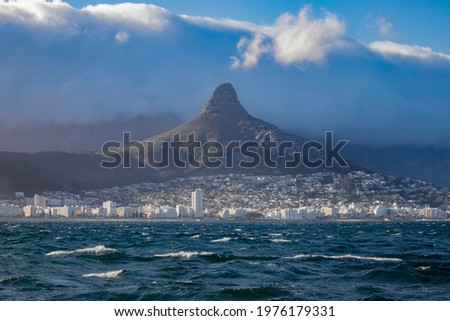 Cape town with characteristic Lion`s Head mountain and the spectaclar Table Cloth cloud roller falling down fro Table Mountain in stormy weather
