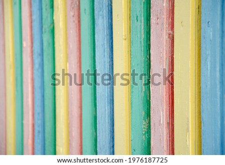 Selective focus multi-colored palisade made of wooden boards. The texture of cracked old paint on wooden planks. The surface of the playground fence. Cozy concept.