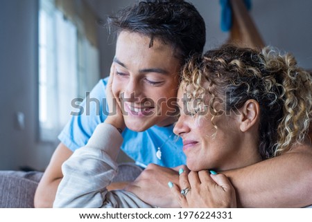 Portrait of middle age mother spend time with teenager son, relatives people hugging at home, adult attentive millennial grateful child wrapped in a plaid or warm sweater loving mommy caring Royalty-Free Stock Photo #1976224331