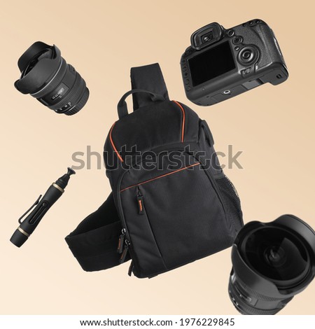 Different professional photography equipment falling on beige background Royalty-Free Stock Photo #1976229845