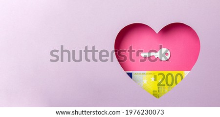 The key to the door and the two hundred euro banknote are in a pink heart on a purple background. Minimal concept of money, love and real estate. Copy space.