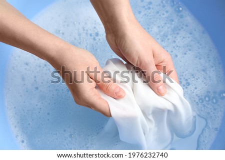 Top view of woman hand washing white clothing in suds, closeup Royalty-Free Stock Photo #1976232740