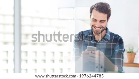 Composition of smiling man using smartphone in office with white overlay. global networking, business and technology concept digitally generated image.
