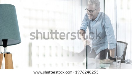 Happy senior businessman standing shaking hand of colleague in office with double exposure. global business, partnership and success concept digitally generated image.