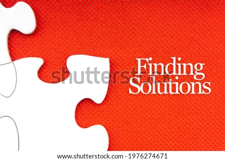 FINDING SOLUTIONS text with jigsaw puzzle on red background. Business and Motivation Concept
