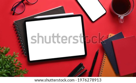 Top view digital tablet, smart phone, notebook, and coffee cup on red background.