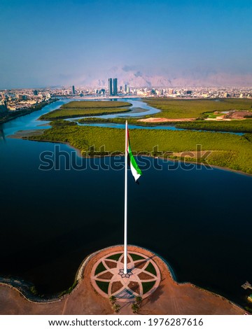 UAE national flag pole and Ras al Khaimah emirate in the northern United Arab Emirates aerial skyline landmark and skyline view above the mangroves and corniche downtown area Royalty-Free Stock Photo #1976287616