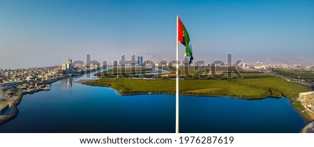 UAE national flag pole and Ras al Khaimah emirate panoramic view in the northern United Arab Emirates aerial skyline landmark and skyline view above the mangroves and corniche downtown area Royalty-Free Stock Photo #1976287619