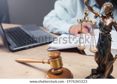 the judge sits in front of the gavel and statues of justice Royalty-Free Stock Photo #1976365223