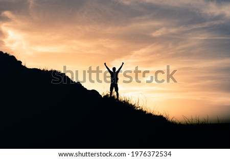 Happy man in nature celebrating victory on top the mountain. Will power, and people adventure concept.  Royalty-Free Stock Photo #1976372534