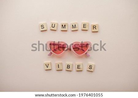 Layout. Pink glasses in the form of hearts on a light pink background. Inscription of wooden blocks Summer vibes